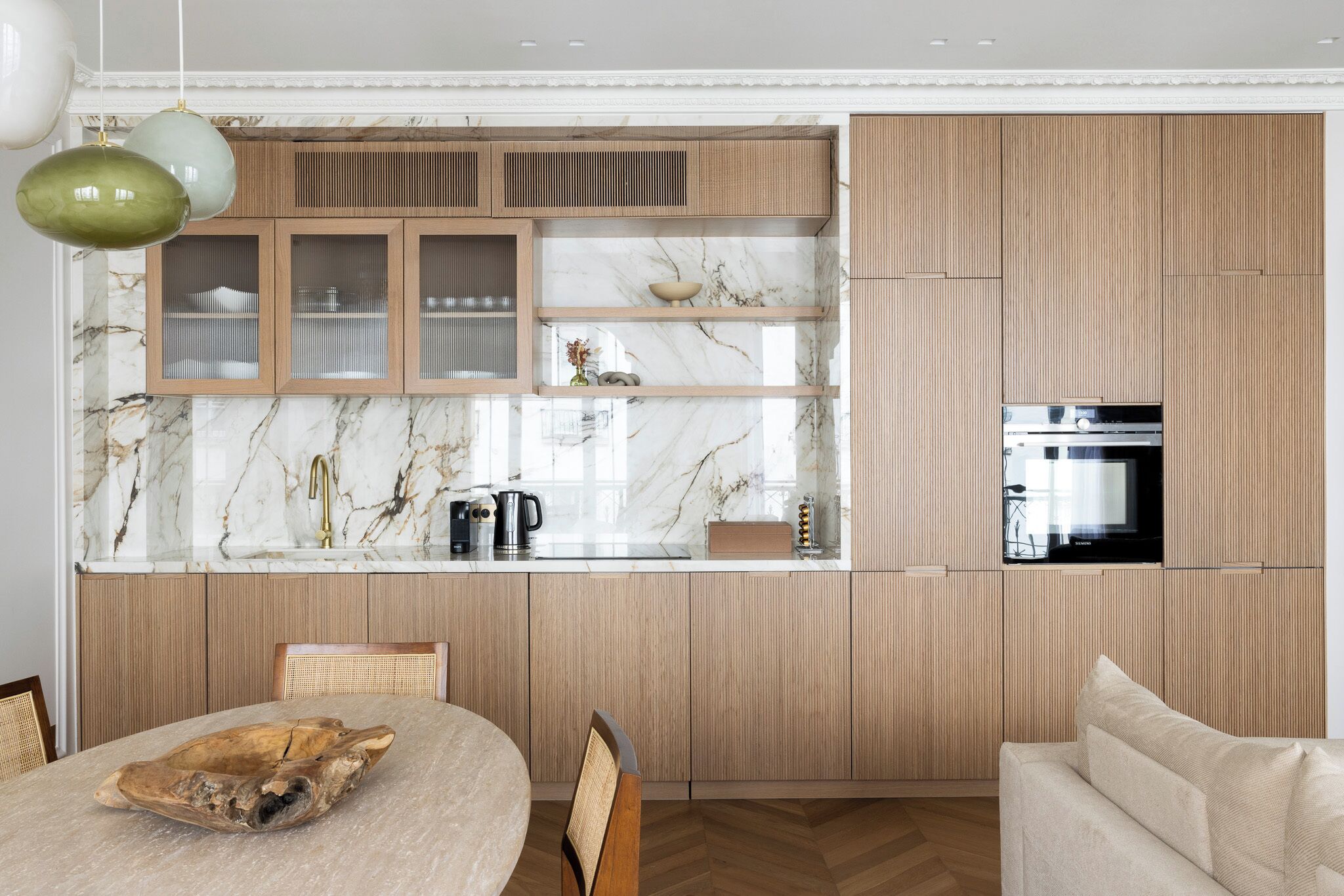 A modern kitchen with wooden cabinets, a marble countertop, and a built-in oven.