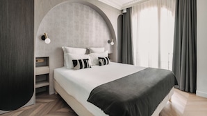 A modern bedroom with a large bed, a curved headboard, and a built-in nightstand. - HIGHSTAY - Luxury Serviced Apartments - Centre Pompidou Museum (Paris)