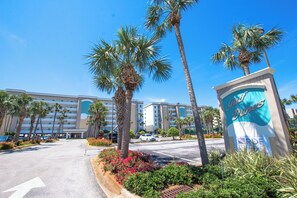A hotel entrance with palm trees, a road, and a sign for 'Giles Dines.'