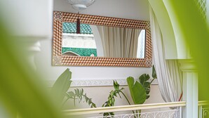 Eine Treppe mit Geländer, einem Blumentopf und einem Spiegel mit geometrischem Rahmen.