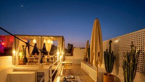 Eine Dachterrasse mit Tischen, Stühlen und Kakteen in Töpfen.