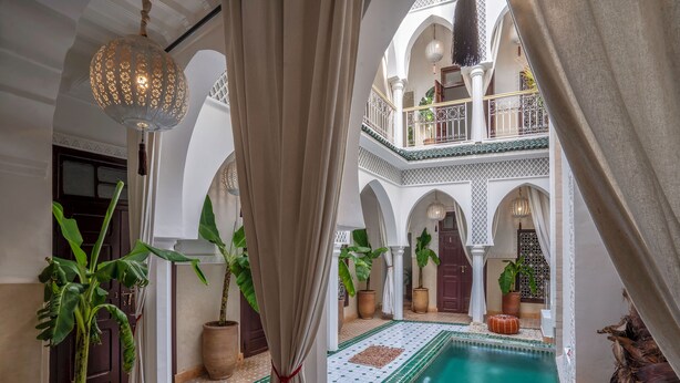 Ein Innenhof mit Schwimmbecken, Blumentöpfen und einer hängenden Lampe.