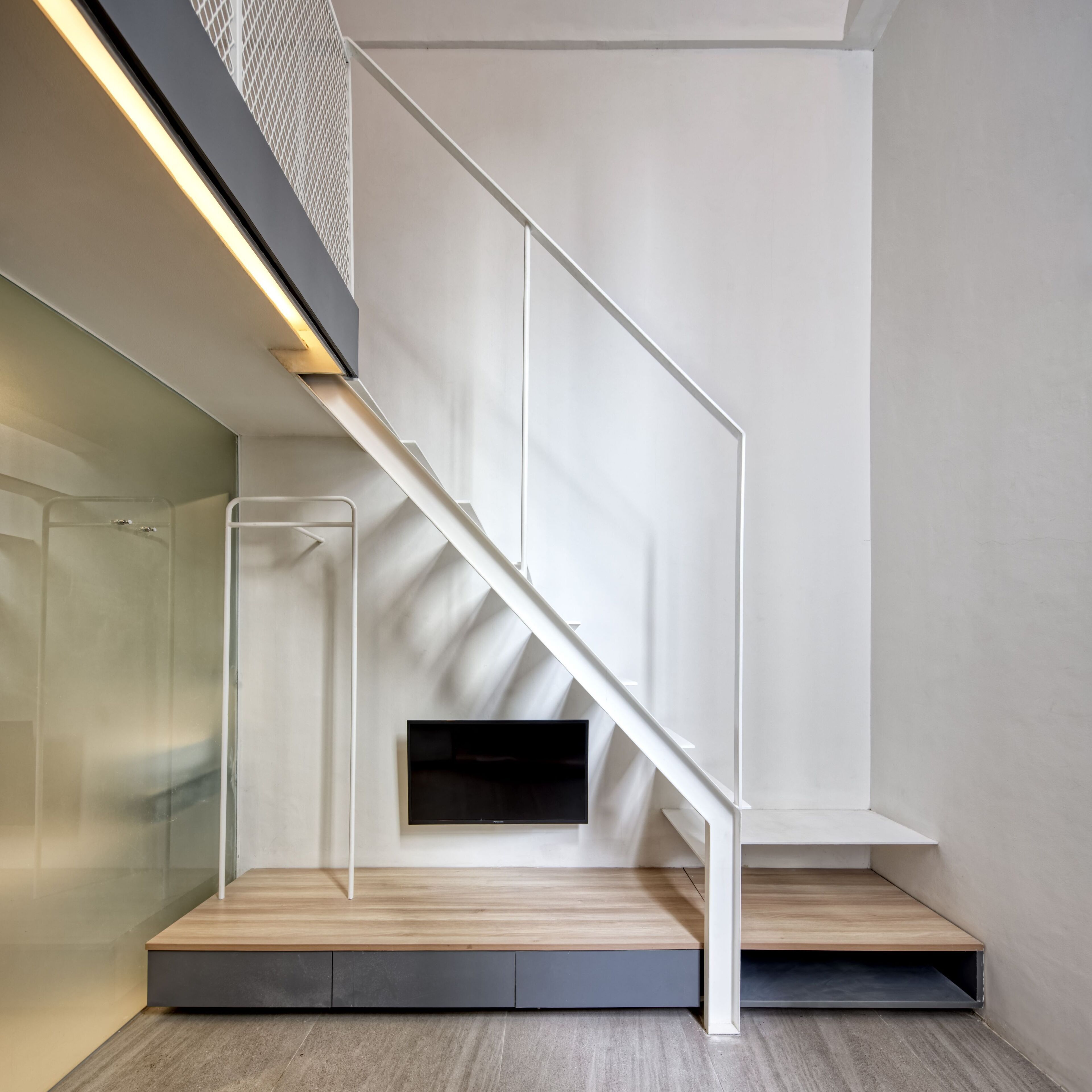 A modern staircase with a minimalist design, a glass enclosure, and a built-in bench.
