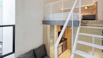 A modern loft bedroom with a bunk bed, a small kitchenette, and a sofa.