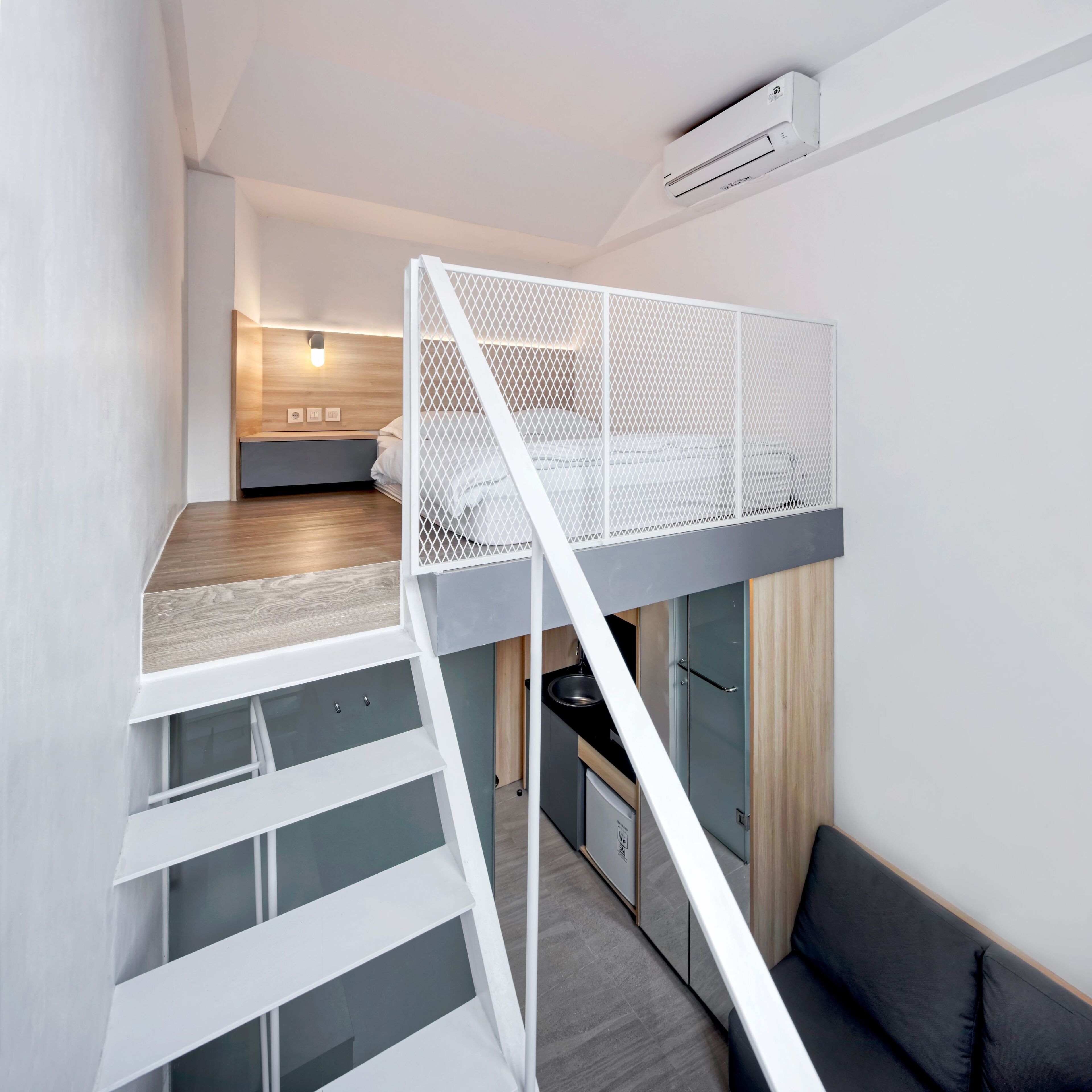 Ein modernes Schlafzimmer im Loft-Stil mit Etagenbett, einer kleinen Küchenzeile und einer Treppe.
