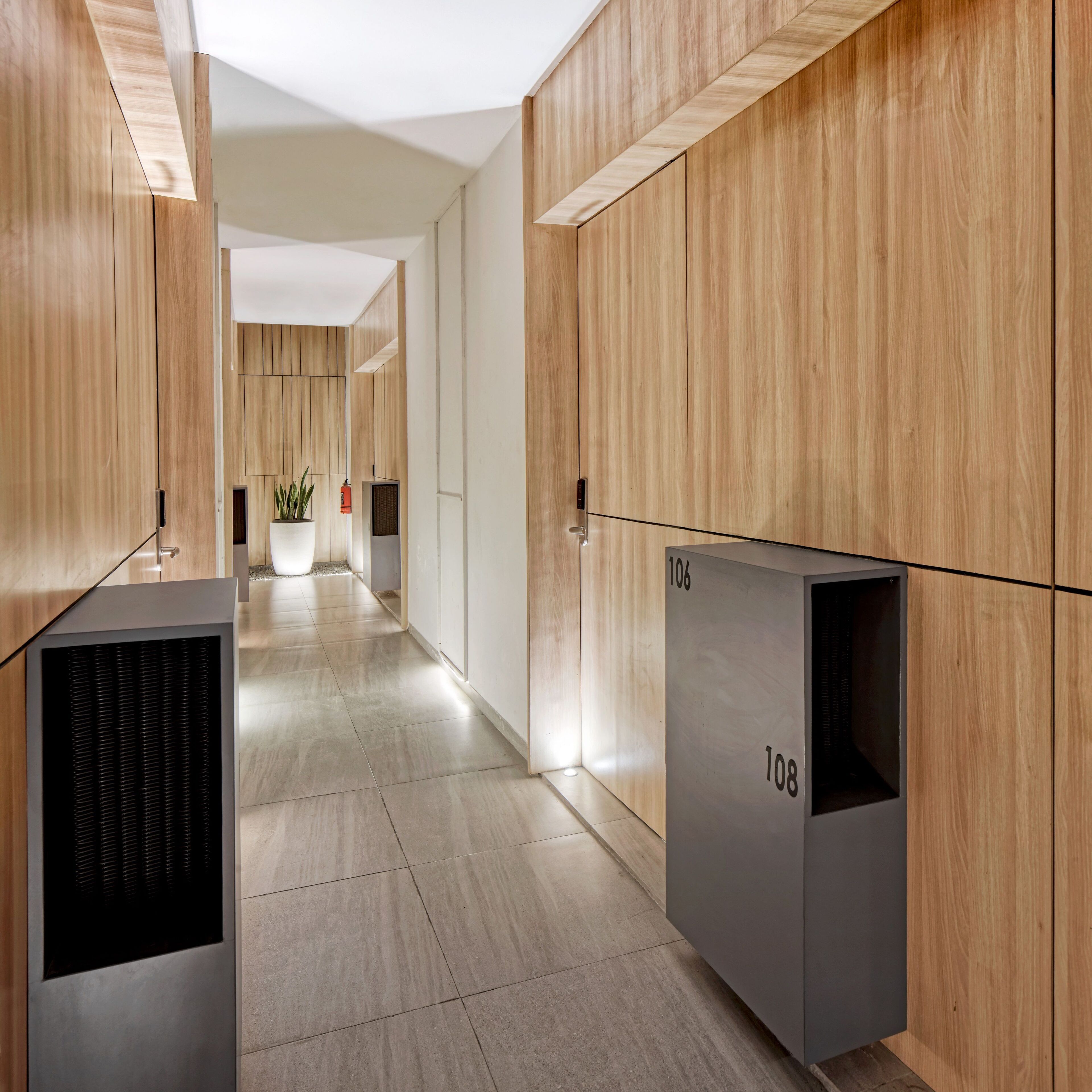 Un couloir moderne avec des lambris en bois et des portes numérotées, donnant accès aux différentes pièces.