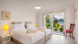 Ein Schlafzimmer mit zwei Betten, einem Sessel und Blick ins Freie.