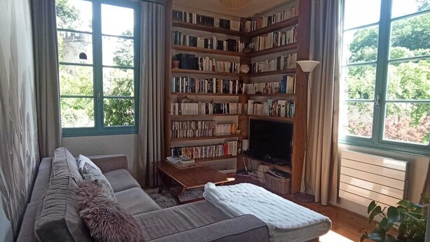 Un accogliente soggiorno con una grande libreria, un divano e un caminetto.