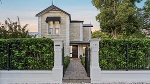 A two-story stone house with a paved driveway leading to a gated entrance. - Sandstone Villa In City Fringe Location (Fullarton)