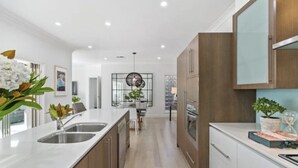 A modern kitchen with a central island, stainless steel appliances, and wooden cabinets. - Sandstone Villa In City Fringe Location (Fullarton)