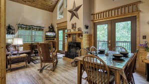 Interior acogedor de una cabaña con chimenea, mesa de comedor de madera y un gran adorno en forma de estrella en la pared.