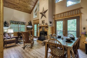 Interior acolhedor de uma cabana com lareira, mesa de jantar de madeira e uma grande decoração em forma de estrela na parede.