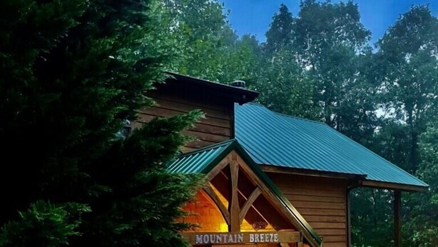 Una cabaña de madera con techo verde y un cartel que dice "Mountain Breeze".
