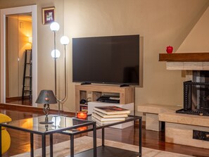 Een moderne woonkamer met een flatscreen televisie, een glazen salontafel, een vloerlamp en een open haard.