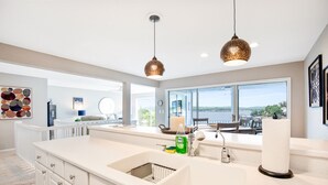 A modern kitchen with a large island, pendant lighting, and a view of the outdoors.