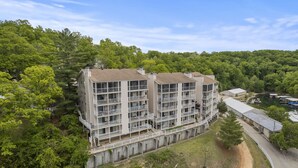 A multi-story building with balconies, surrounded by dense forest.