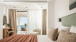Habitació d'hotel moderna amb un llit gran, una taula de treball, una cadira i vista al mar.