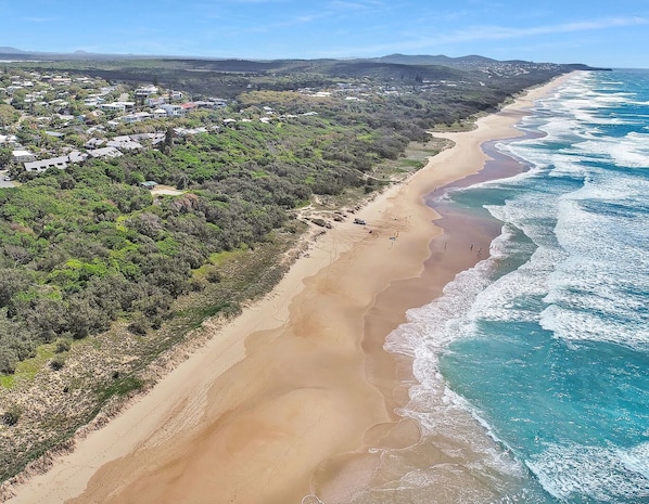 Enjoy a serene beach experience surrounded by lush greenery.