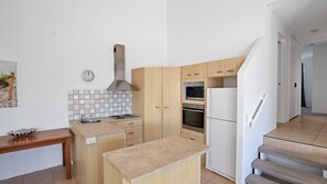 Enjoy cooking in this well-equipped kitchen with an oven, stainless steel range hood, and a convenient island with sink and countertop.