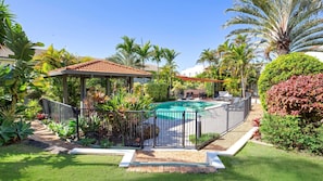 Relax by the pool surrounded by lush tropical vegetation and a shaded gazebo.