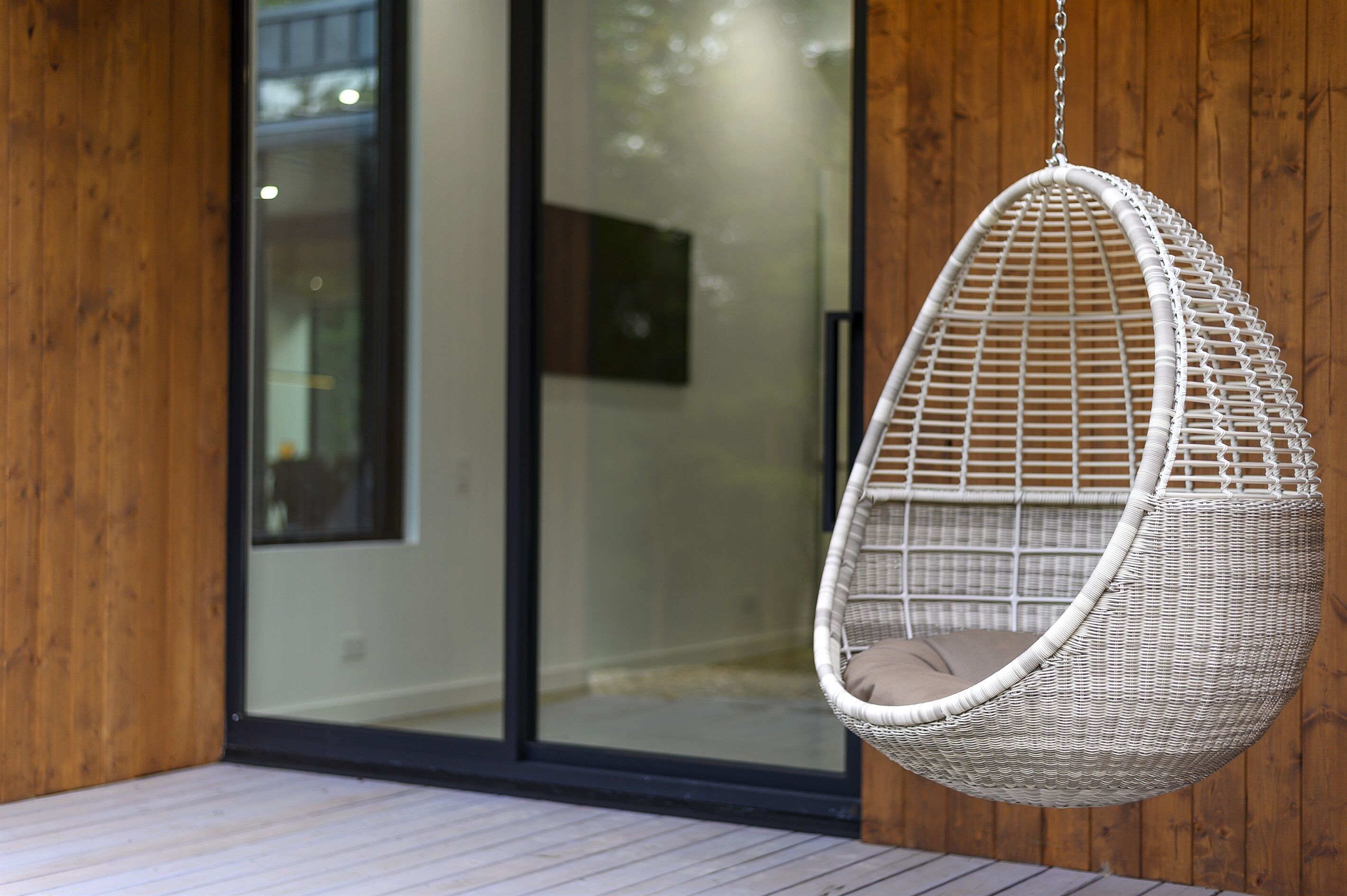A hanging chair with a woven seat and back, suspended from a ceiling.