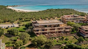An aerial view of a coastal resort with multiple buildings, a beach, and a clear view of the sea. - Rena Bianca House by Wonderful Italy (Olbia)