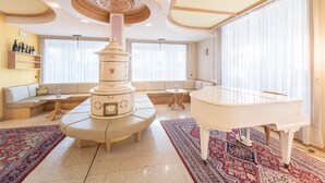 Un vaste salon agrémenté d’un piano blanc, d’une colonne décorative et d’un canapé.