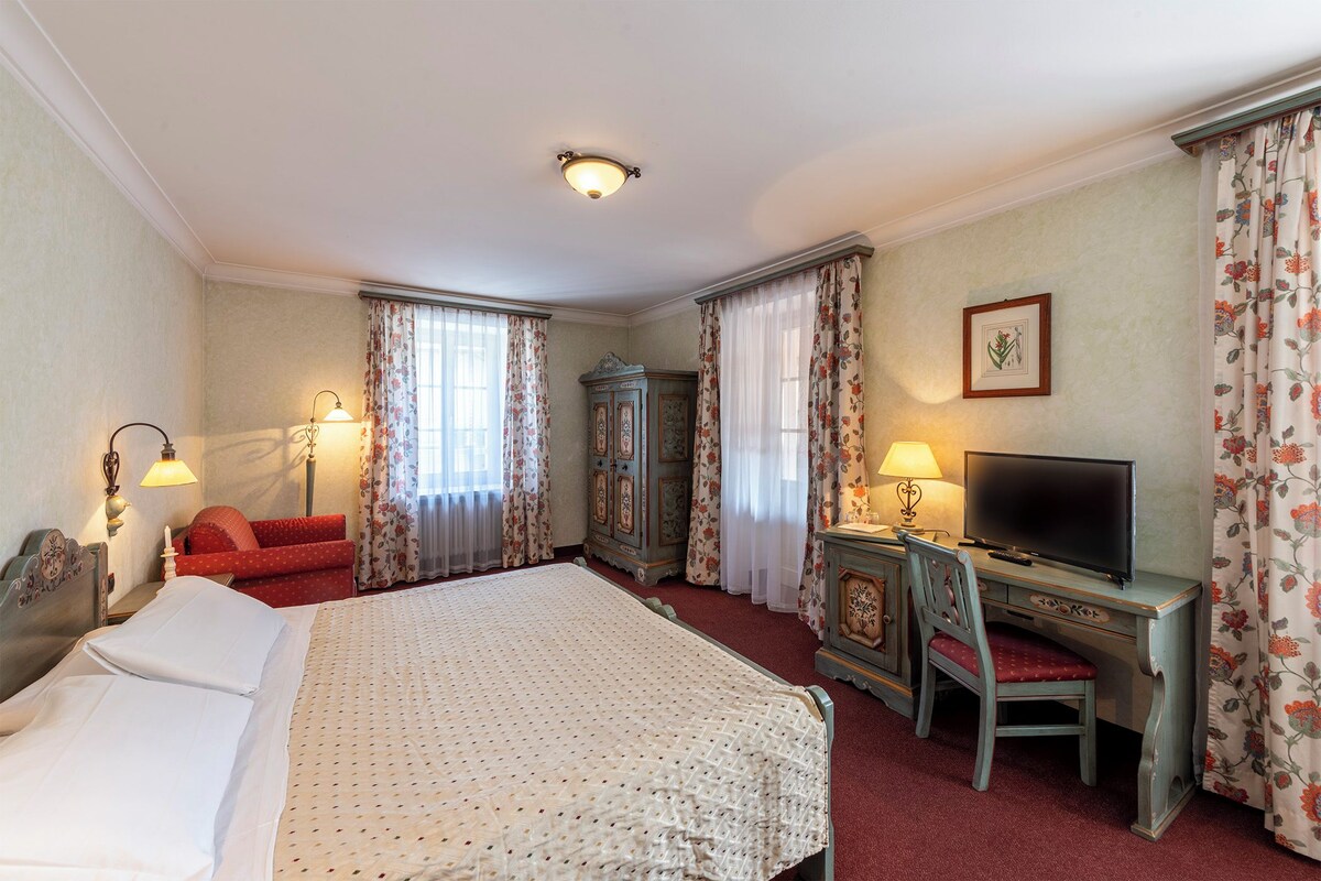 Une chambre d’hôtel comprenant un lit, un bureau avec une chaise, une télévision et une armoire.