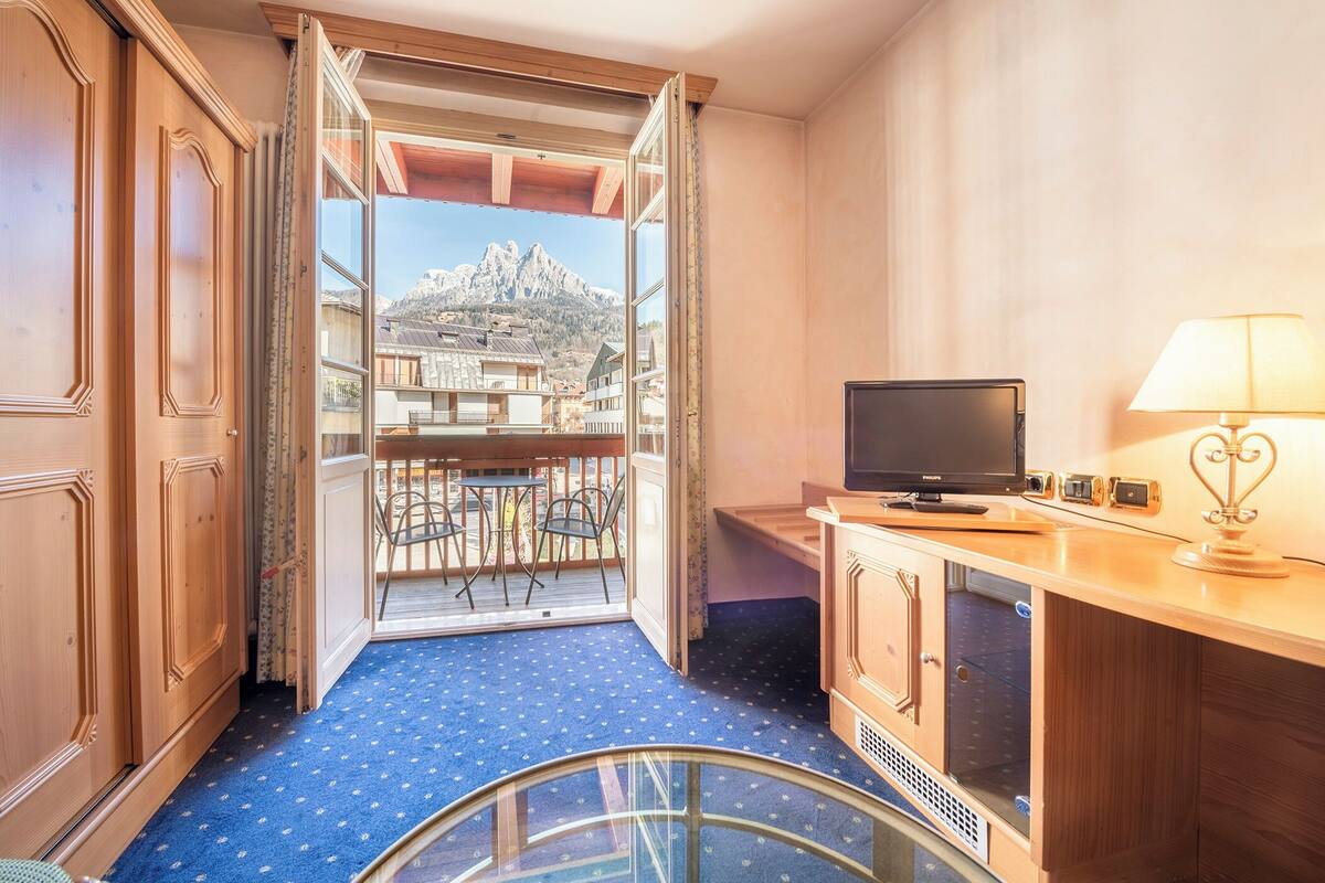 Ein Hotelzimmer mit Balkon, Fernseher und Lampe.