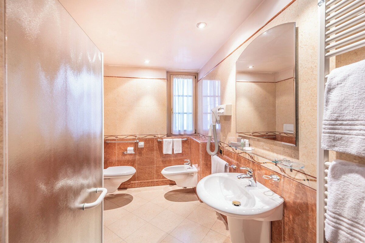 Une salle de bain moderne dotée d’une douche à parois de verre, d’un grand miroir et d’un meuble-lavabo avec un évier et un porte-serviettes.