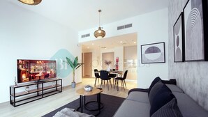 Un salon moderne avec un canapé, une table basse et un téléviseur. Il y a également un coin repas avec une table et des chaises.