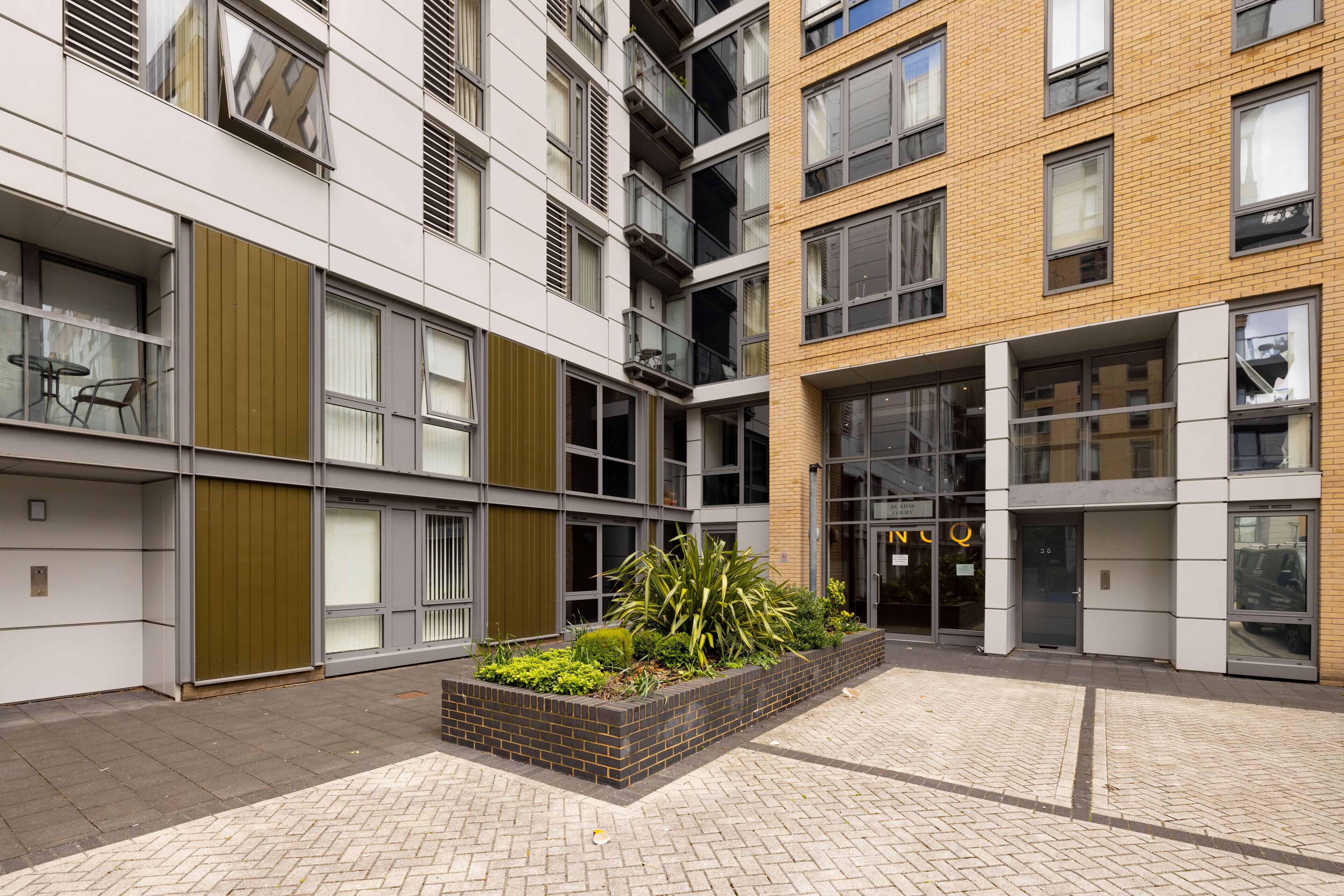 Un edificio moderno de varios pisos, con amplios ventanales y un patio central con plantas.