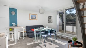 Ein modernes Wohnzimmer mit Esstisch, Stühlen, einer Couch und einem großen Fenster.