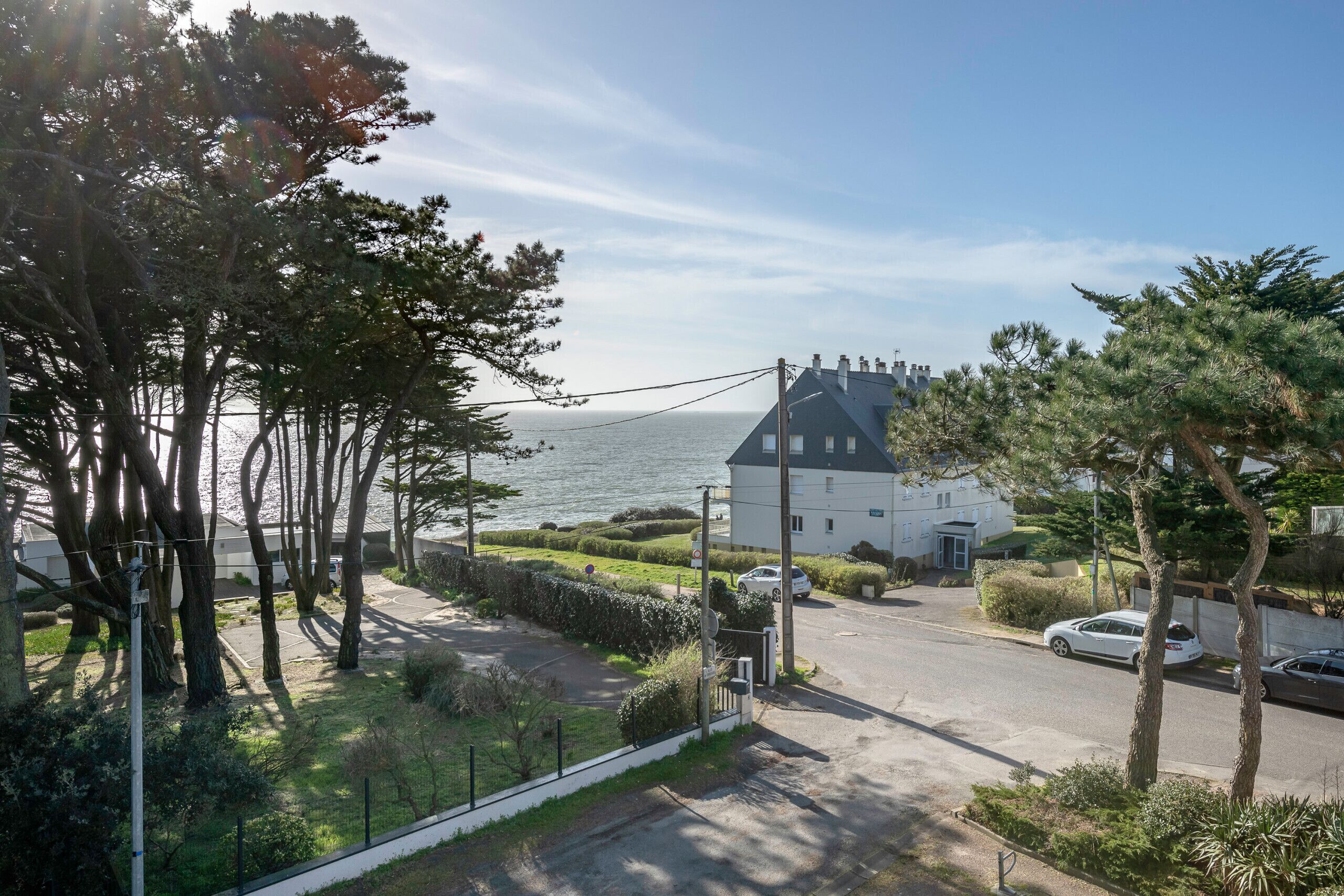 Ein Wohngebiet mit einem großen weißen Haus, einer gepflasterten Auffahrt und Blick auf das Meer.