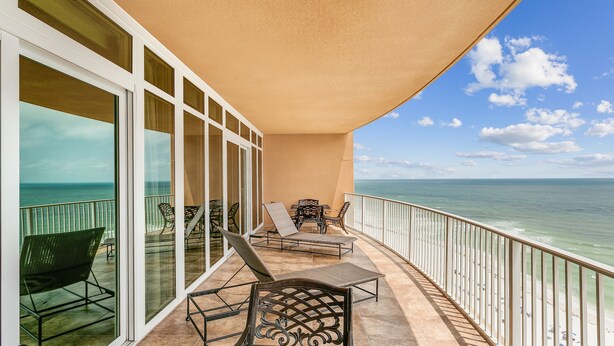 A balcony with a view of the ocean, furnished with chairs and a table. - Phoenix Orange Beach!  Lazy River and Slide !  New Rental!! (Orange Beach)