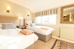 Two single beds with neatly made linens and lamps create a warm and inviting atmosphere.