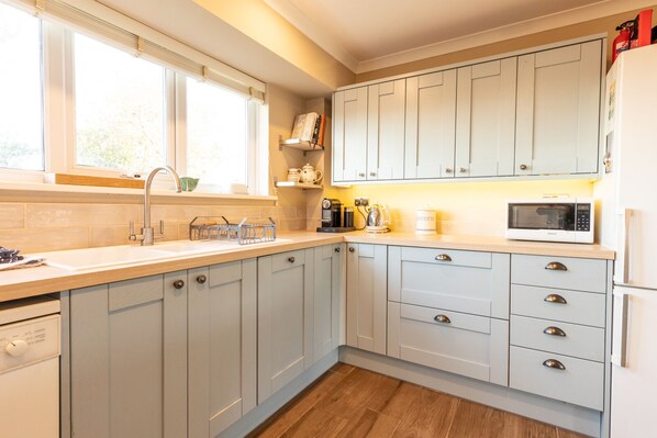 Kitchen features a dishwasher, stainless steel sink, and refrigerator.