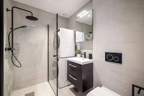 A modern bathroom with a glass-enclosed shower, a white vanity with a black cabinet, and a wall-mounted mirror. - Meltzers Apartment  (Bergen)