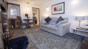 A living room with a grey sofa, a wooden cabinet, a fireplace, and a framed picture on the wall. - Pretty dog friendly cottage for two in the heart of the Georgian town of Richmond, North Yorkshire (Richmond)