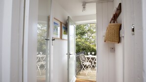 A doorway leading to an outdoor patio with white metal chairs and a table, a woven basket on the wall, and a view of trees. - Pretty dog friendly cottage for two in the heart of the Georgian town of Richmond, North Yorkshire (Richmond)