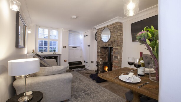 A cozy living room with a fireplace, a dining table set for two, and a comfortable sofa. - Pretty dog friendly cottage for two in the heart of the Georgian town of Richmond, North Yorkshire (Richmond)