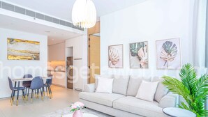 A modern living room with a sofa, a round coffee table, and a dining area with chairs. - HomesGetaway-1Bedroom in JBR The Address (Dubai)