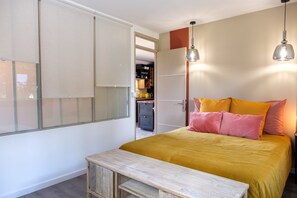 Une chambre à coucher avec un lit, des tables de chevet, une armoire et une fenêtre.