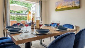 Ein Esstisch gedeckt mit blauen Tellern, Weingläsern und einer Flasche, mit einem Gemälde eines Leuchtturms an der Wand.