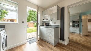 Eine moderne Küche mit grauen Schränken, einem eingebauten Backofen und einer Waschmaschine in der Nähe des Fensters.