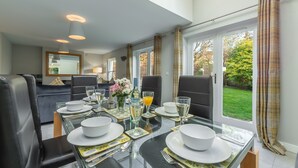 Een eetgedeelte met een glazen tafel voor vier personen, omringd door zwarte lederen stoelen.