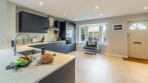 Een moderne keuken met donkere kastjes, een centraal eiland en uitzicht op de omgeving.