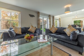 Relax in this inviting living room with a glass coffee table, dark grey sofas, and a brick accent wall.