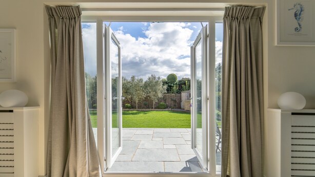 An open sliding glass door leading to a patio with a lawn and garden. - Drifters, Thornham, Norfolk (Thornham)