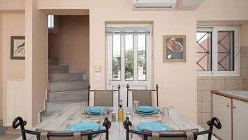 A dining area with a table set for four, a staircase leading to an upper floor, and a kitchen area with a window.